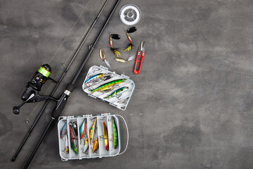 Fishing tackle - fishing spinning rod, hooks and lures on gray background. Active hobby recreation...