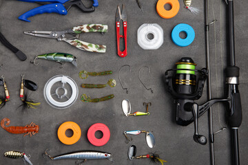 Fishing tackle - fishing spinning rod, hooks and lures on gray background. Active hobby recreation...