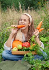  10 year old girl eats fresh carrots and other vegetables and sits on the grass