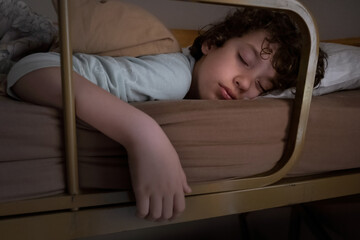 Little boy sleeping on a bunk bed. Cute boy dreaming blissfully.