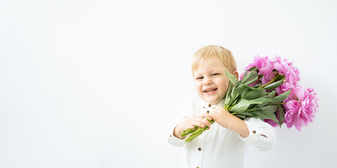 Obraz na płótnie Canvas banner. little blonde boy with big bouquet of pink peonies on white background. Love and romantic concept