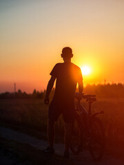 Fototapeta na wymiar The silhouette of a cyclist at sunset in a field. Cycling on a summer evening