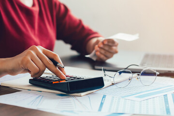 Close up woman hand using a calculator and the other hand holds the bill with calculate about...