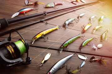 Fishing tackle - fishing spinning rod, hooks and lures on wooden background. Active hobby...