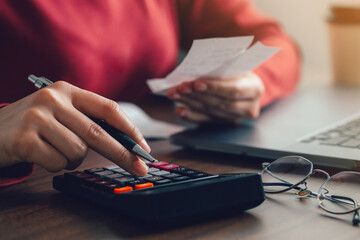 Women using calculators calculate domestic bills at home. Young women checking balance costs and...