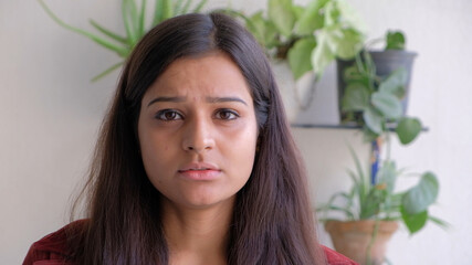 Closeup of a young South Asian woman looking directly into the camera with a sad concerned face