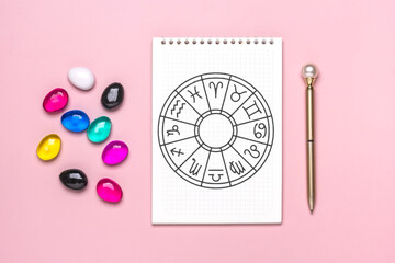 Horoscope circle with twelve signs of zodiac on paper, divination dice, colorful stone on pink...