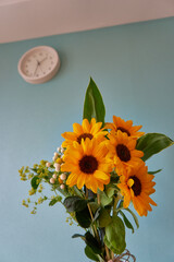 インテリアとして室内に飾られているヒマワリの花束と時計