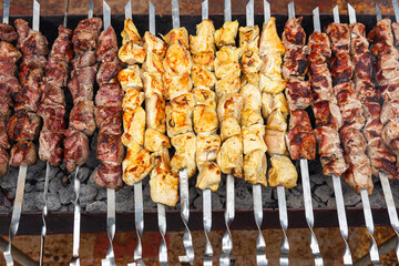 Three types of meat on skewers on the grill. Pieces of pork, chicken and lamb on skewers on the grill.