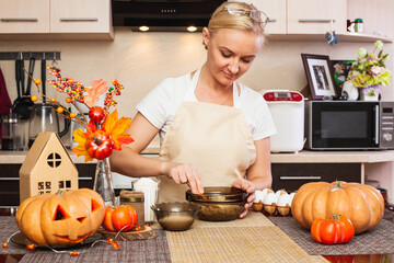 A woman kneads cookie dough for Halloween in the kitchen with autumn decor.