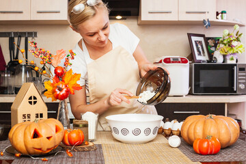 A woman puts cottage cheese in cookie dough for Halloween in the kitchen with autumn decor.