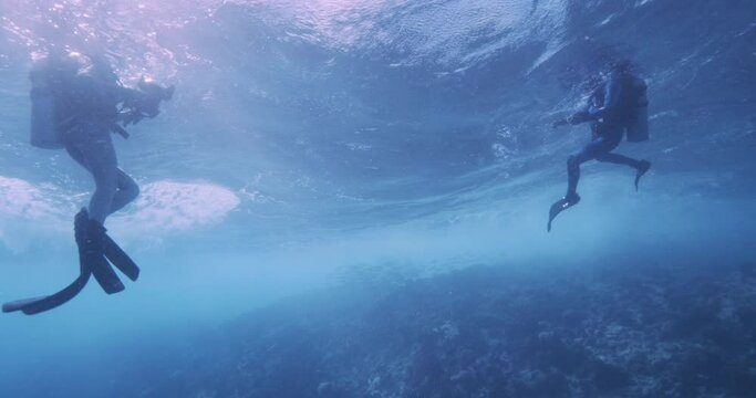 Scuba divers on surface very rough water from underneath.