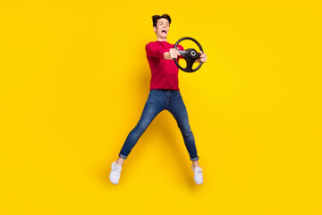 Fototapeta na wymiar Full length photo of cute shocked young guy dressed red pullover driving car jumping isolated yellow color background