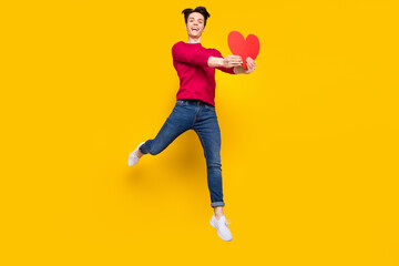 Fototapeta na wymiar Full body photo of funky brunet millennial guy jump give heart wear red sweater jeans isolated on yellow color background