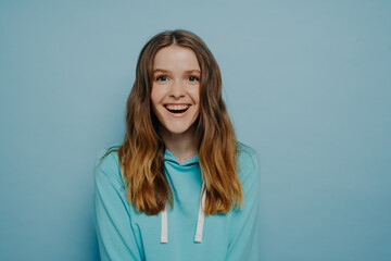 Fototapeta premium Laughing teenager wearing casual hoodie looking with positive expression at camera