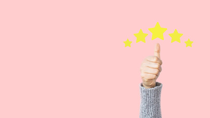 Woman hand showing thumb up with giving a five star rating on pink background. Service rating,...
