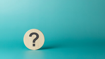 Wooden sphere with question mark on green background. Business concept