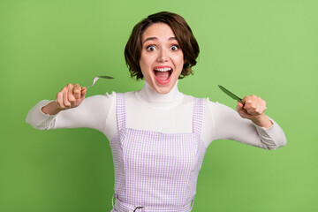 Photo portrait woman keeping fork knife in restaurant crazy hungry isolated pastel green color...