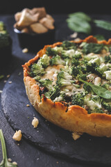 Millet quiche with spinach, salmon, broccoli and ricotta on dark wooden table. Homemade 
vegetarian cake. Copy space for text. Fresh pie with soft cheese. Healthy food. French cuisine