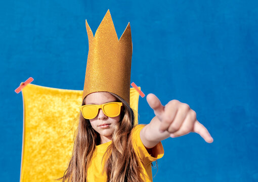 Teenager in crown and sunglasses showing shaka gesture