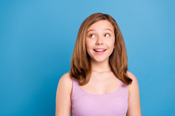 Photo of optimistic brown hairdo teenager girl look empty space wear violet top isolated on blue...