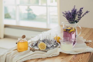 Fresh lavender lemonade, lemons, honey, lemon juice and glasses on a kitchen table.