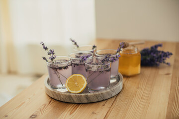Fresh lavender lemonade and jar with honey on a kitchen table.
