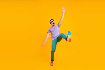 Photo of charming sweet young gentleman wear violet t-shirt dark eyewear smiling dancing isolated yellow color background