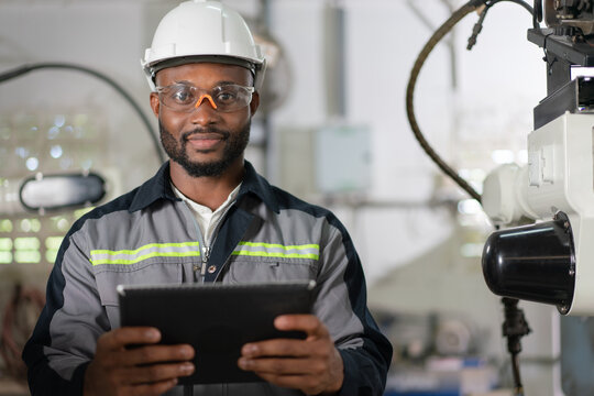 Portrait of male automation engineer hold tablet for inspection robot arm welding machine  in industrial factory