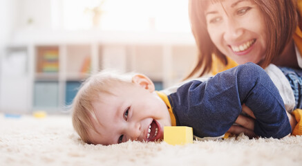 Mother playing with her cute son on the floor