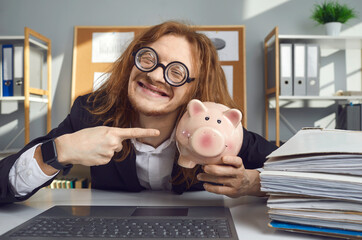 Proud satisfied young man in funny glasses holding piggy bank and smiling. Crazy happy nerdy office...