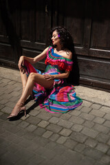 Spectacular sensual beautiful European woman with curled dark hair in a summer dress in the city