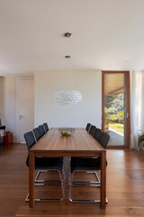 Front view dining room with wood table, leather chairs and dark hardwood floors. Stylish modern home