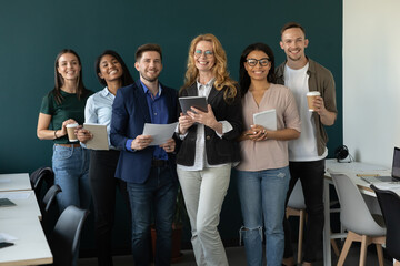 Happy diverse business team, staff, employees of different ages, generations, races smiling at camera. Group office portrait of mature female leader, teacher with young multiethnic workers