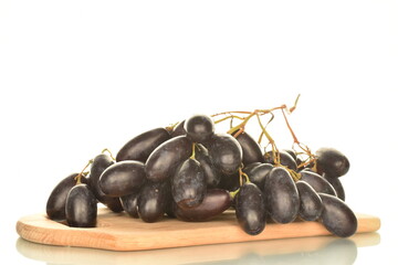 One bunch of ripe black grapes on a wooden board, close-up, isolated on white.