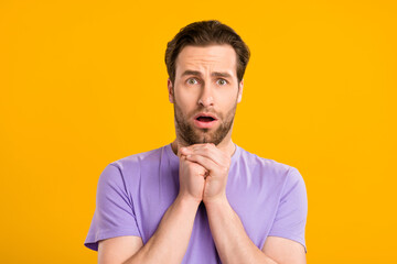 Photo of scared worried guy pleading face hold hands wear violet t-shirt isolated yellow color background