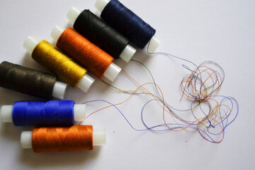 Row of multicolored spools of sewing threads on a white table. Workplace of seamstress. Sewing background with copy space.