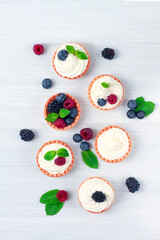 Mini tartlets with whipped cream and fresh berries, on a white table, blurred focus, horizontal, no...
