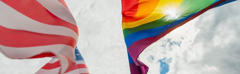 bottom view of american and colorful lgbt flags against sky, banner