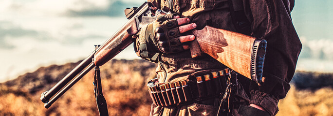 Hunting period, autumn season. Male with a gun. Hunter with a backpack and a hunting gun. A hunter...