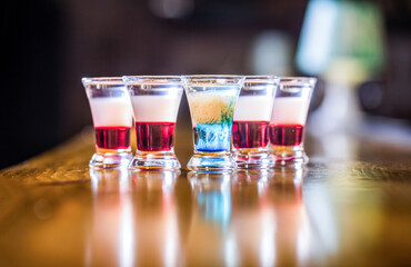 Colorful shots at the club. Alcoholic drink in different colors. Shots at the bar table. Alcoholic drinks in shot glasses. Tequila shots, vodka, whisky. Set of alcoholic cocktails in shot glasses