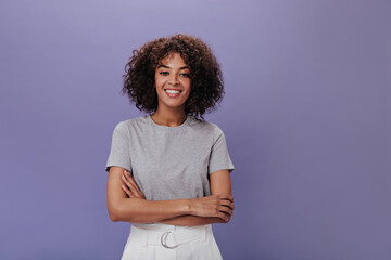 Portrait of young girl in gray t-shirt on purple background. Closeup snapshot of curly brunette...