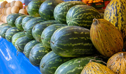 Ripe melons and watermelons, farmers market counter, harvest sale. Background image with place for text.