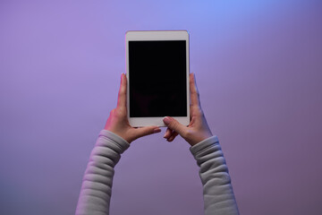 Close-up of hands with tablet and blank black screen.