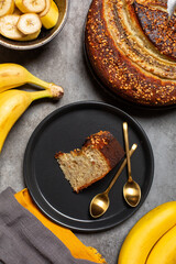 A piece of banana bread with hazelnuts. Grey background, vertical image.
