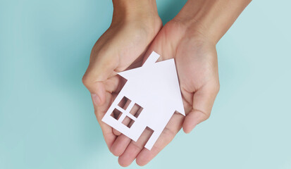 Hands holding paper house, family home protecting insurance concept