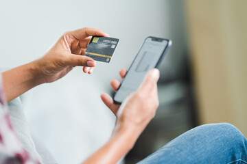 Close-up of a businessman’s hand holding credit card and using laptop at home. Businessman or entrepreneur working, online shopping, e-commerce, internet banking, working from home concept