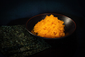 Tobiko egg is orange (flying fish roe) on white plate. Fushion food style Japanese for cooking rice don,nikiri or sushi side view isolated on white background.