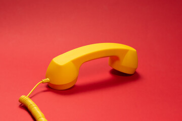 Yellow handset on red background.