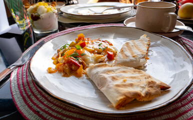 Scrambled eggs with lavash roll, coffee in a cup.